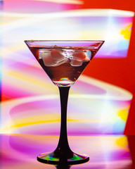 glass with cocktail and ice on a beautiful background with neon stains