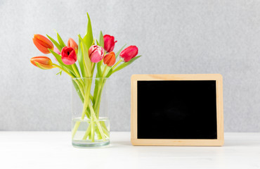 colorful tulips in a Vase with gray background and chalkboard