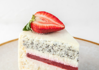 A slice of strawberry cake on a gray plate. Decorated with strawberries. Close-up. On a white background.
