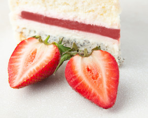 A slice of strawberry cake on a gray plate. Decorated with strawberries. Close-up. On a white background.
