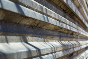 Fragment of an old fence of an abandoned construction site, made of metal sheets. Sunlit fragment of the fence