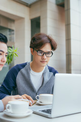 Two young businessmen are chatting in a coffee shop. - Image