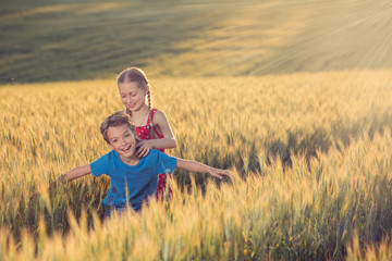 Naklejka na ściany i meble lifestyle concept, a boy and a girl are in the middle of a yellow wheat field, interact and laugh merrily, gestures and emotions