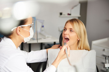 Obraz na płótnie Canvas Focused dentist with dental drill cleaning bad patient's teeth