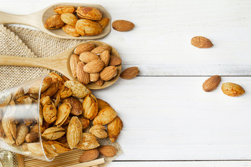 Almonds in a black bowl against dark rustic wooden background
