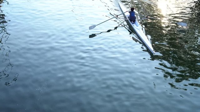 Rowers training on a competition rowing boat in a water canal. View from above.