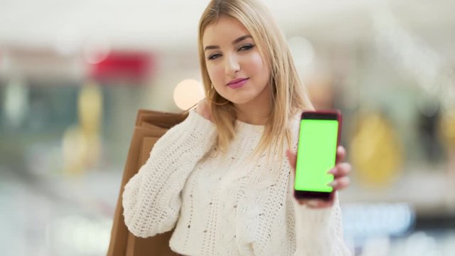 Young girl holding shopping bags and chroma key phone