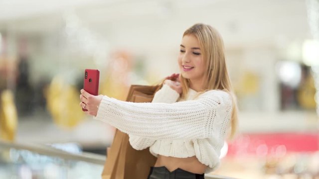 Beautiful blonde smiling and taking photos of herself at the mall