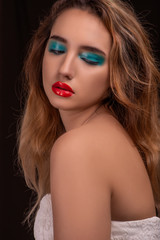 Fototapeta premium Attractive blonde with bright stylish make-up . Colored Smokey eyes with wet eyelid effect. Fashion portrait on a black background