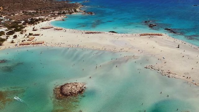 Epic aerial shot of Elafonissi beach with a surfer paragliding in Crete, Greece