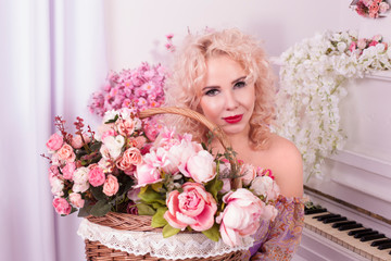 beautiful young woman with flowers in a basket on the background of a piano