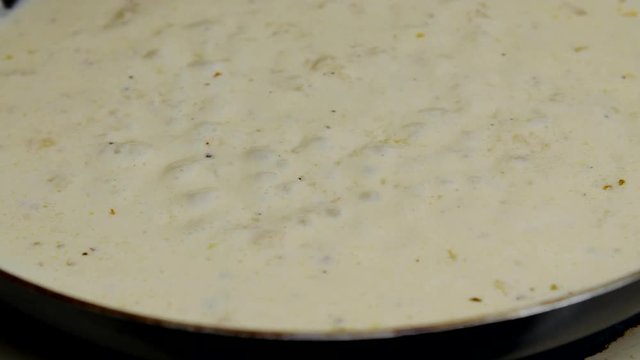 Alfredo sauce simmers on the stove top.