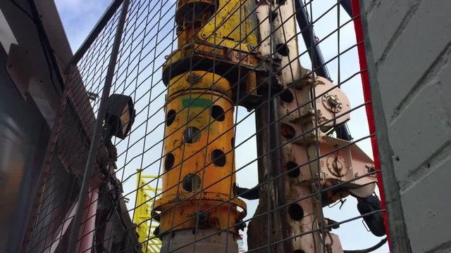Wide shot showing the rotating positioning of the boring column on a hydraulic rotary drilling rig as it enters boring hole