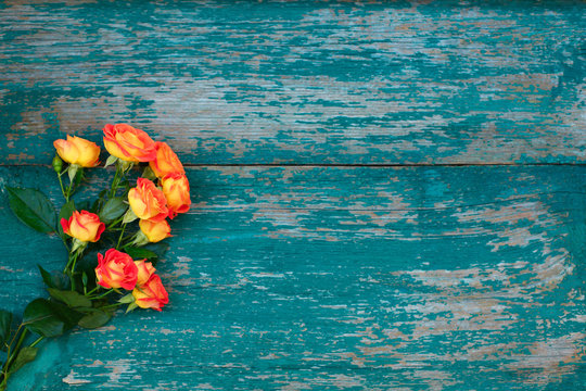 Background of a bouquet of beautiful fresh vivid orange roses for celebrating Valentines, birthday or Mothers Day on green wooden background