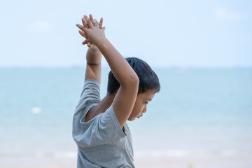 Fototapeta na wymiar little kid boy stand on beach and stretch oneself