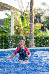 Happy asian kid boy swiming on swiming pool in the summer