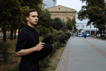 attractive guy in a hat on the street, in black, hat