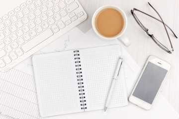 Flat lay photo of white office desk with laptop, smartphone, eyeglasses, notebook and pen with copy space background. Mockup