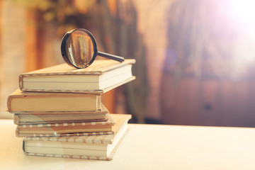 book and magnifying glass on wooden background