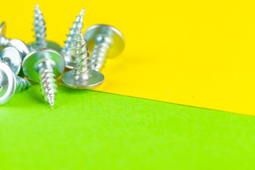 Top view of stainless steel bolts or iron nails on bright green background