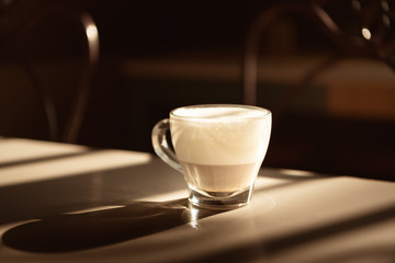Italian typical cappuccino in a glass cup on a grey table