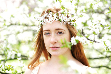 Obraz premium Beautiful redhead girl surrounded by blooming trees. Spring season is magic.