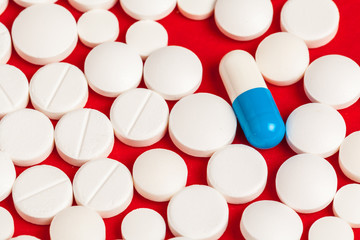 Many medicine pills close up on red background