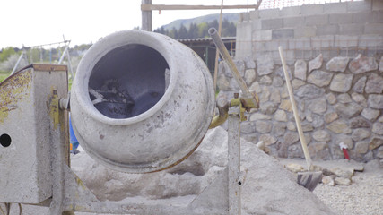 Cement mixer with building rock wall in background in progress