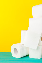 Toilet paper rolls stacked against yellow paper background