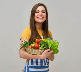 smiling woman wearing striped apron holding vegetables