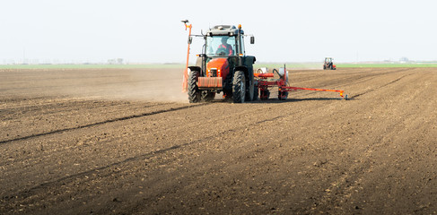 Obraz premium Farmer with tractor seeding sowing crops at agricultural field