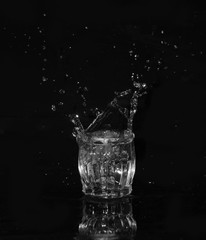 Glass of drinking water. From a glass of water splashes with reflection on a dark background.