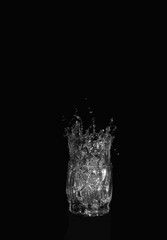 Glass of drinking water. From a glass of water splashes on a dark background.