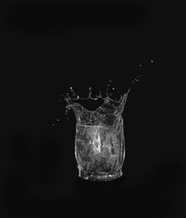 Glass of drinking water. From a glass of water splashes on a dark background.