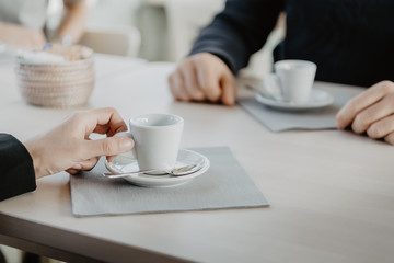 Business meeting in a café: coffee small cup, saucer, coffee spoon and napkin
