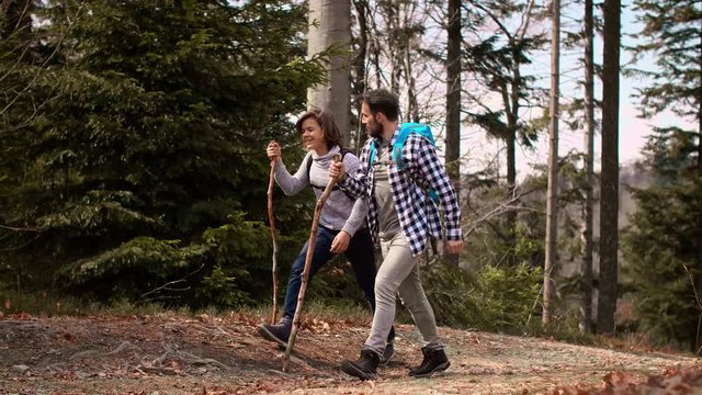 Smiling dad and son with backpack hiking in the forest