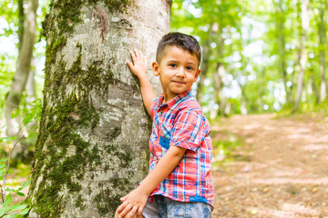 boy in the woods standing near a tree