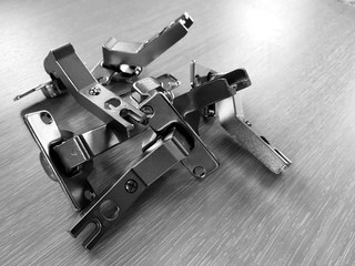 Steel furniture hinges lie on a light wooden texture