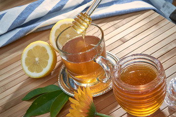 honey dripping from a spoon of honey over a glass of tea.