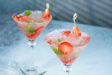 Strawberry lemonade or alcoholic cocktail with ice syrup soda and mint leaves on bar table.