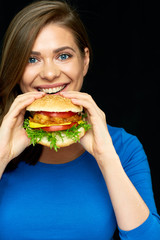 young woman biting burger on black background.