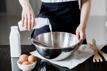 Pouring milk in a bowl of flour