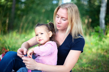 Mother and little daughter blowing soap bubbles outdoor. Parent and kid having fun in park. Happy and carefree childhood. Good family relations.