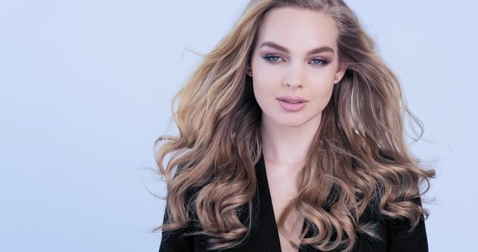 Beautiful young blonde woman with  long hair. Fashion model looks to the camera. Stunning face of a caucasian girl. Sexy model with a beautiful blue eyes. Slow motion. Beauty concept. 4k footage.