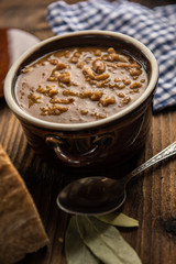 tripe stew sauce in brown ceramic pot on a wood table 