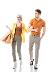 pretty woman holding shopping paper bags while standing near handsome man isolated on white