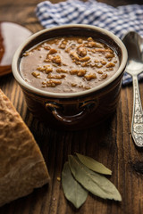 tripe stew sauce in brown ceramic pot on a wood table 