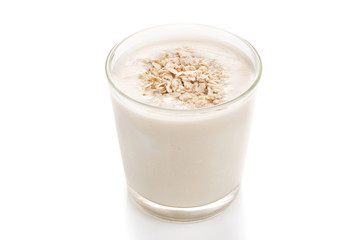 Glass of oat milk and grains on top