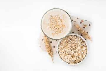 Glass of oat milk and grains in white bowl