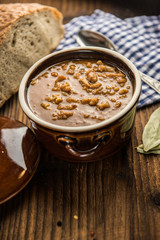 tripe stew sauce in brown ceramic pot on a wood table 